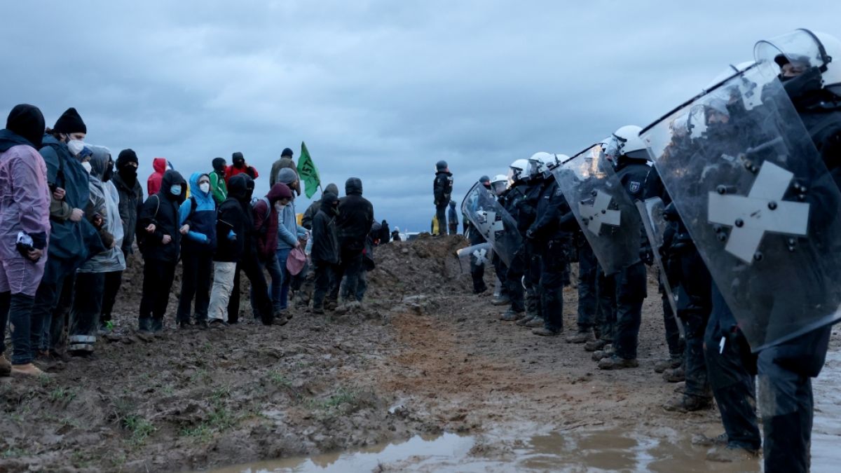 Polizisten und Demonstranten stehen sich bei der Demonstration von Klimaaktivisten am Rande des Braunkohletagebaus bei Lützerath gegenüber. (Foto)