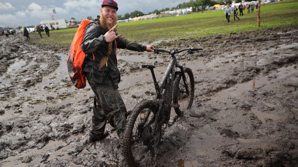 Metal-Fan Lukas Litwin aus Bochum ist mit seinem E-Mountainbike auf dem schlammigen Festivalgelände unterwegs. (Foto)