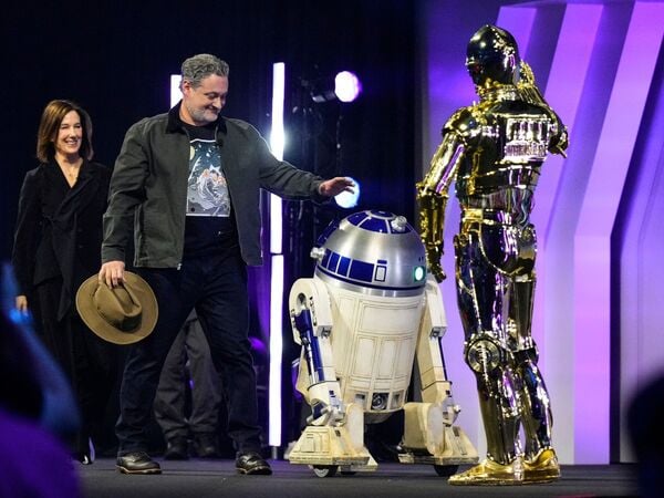 ARCHIV - 18.04.2025, Japan, Chiba: Filmproduzentin Kathleen Kennedy und Regisseur Dave Filoni werden von R2-D2 und C-3PO (r) begrüßt, als sie die Bühne der Star Wars Celebration in Chiba, in der Nähe von Tokio betreten. (zu dpa: «Lucasfilm-Chefin Kennedy tritt ab») Foto: Hiro Komae/AP/dpa +++ dpa-Bildfunk +++