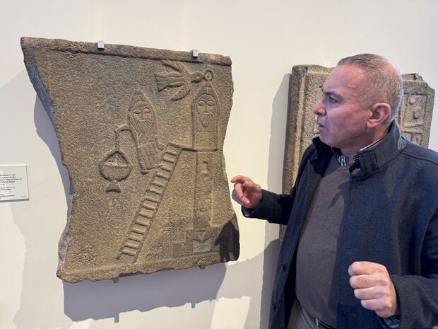 Mohamad Al Subeh vor einer Steinplatte aus Syrien mit der Darstellung Simon des Säulenstehers in Qalat Seman im Nordosten Syriens. Die basaltplatte stammt aus dem 5. bis 6. Jahrhundert. Die Reste der Originalsäule in Qalat Seman wurden während des Krieges bomardiert und zerstört. Foto: Rolf Brockschmidt