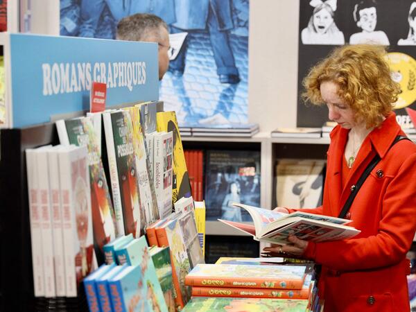 A visitor looks at a comics book at Le Monde des Bulles section during the 51st Angouleme International Comics Festival in Angouleme, southwestern France, on January 26, 2024. (Photo by YOHAN BONNET / AFP)