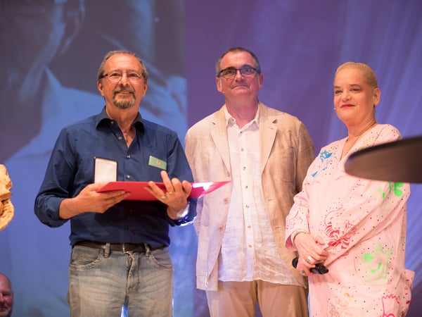 Paul Derouet (links) bei der Max-und-Moritz-Gala 2018, wo ihm der Spezialpreis der Jury verliehen wurde. Neben ihm das Moderations-Duo Christian Copyright: Internationaler Comic-Salon Erlangen – Foto: Erich Malter, 2018
