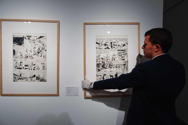 An employee adjusts a framed original plate drawing by Belgian comic artist and illustrator Maurice de Bevere (1923-2001), better known as Morris, displayed at Christie's auction house in Paris on November 8, 2024. (Photo by Dimitar DILKOFF / AFP)